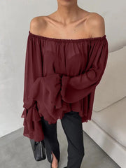 Person wearing a burgundy off-shoulder top with a plain background