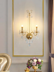 A luxurious crystal wall sconce with a gold finish, illuminating a modern living room. Golden Atelier 2