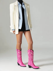 Person wearing pink cowboy boots with a neutral background