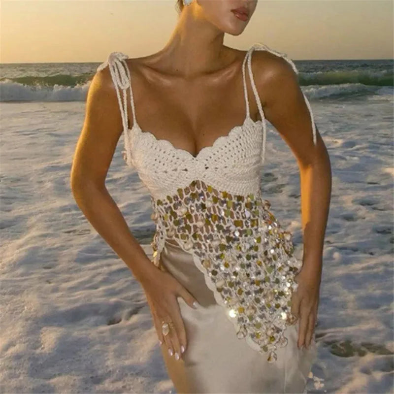 Woman in a white crochet top and patterned skirt on a beach at sunset.