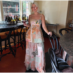 Woman wearing floral print beaded strap top and maxi skirt set holding a wine glass