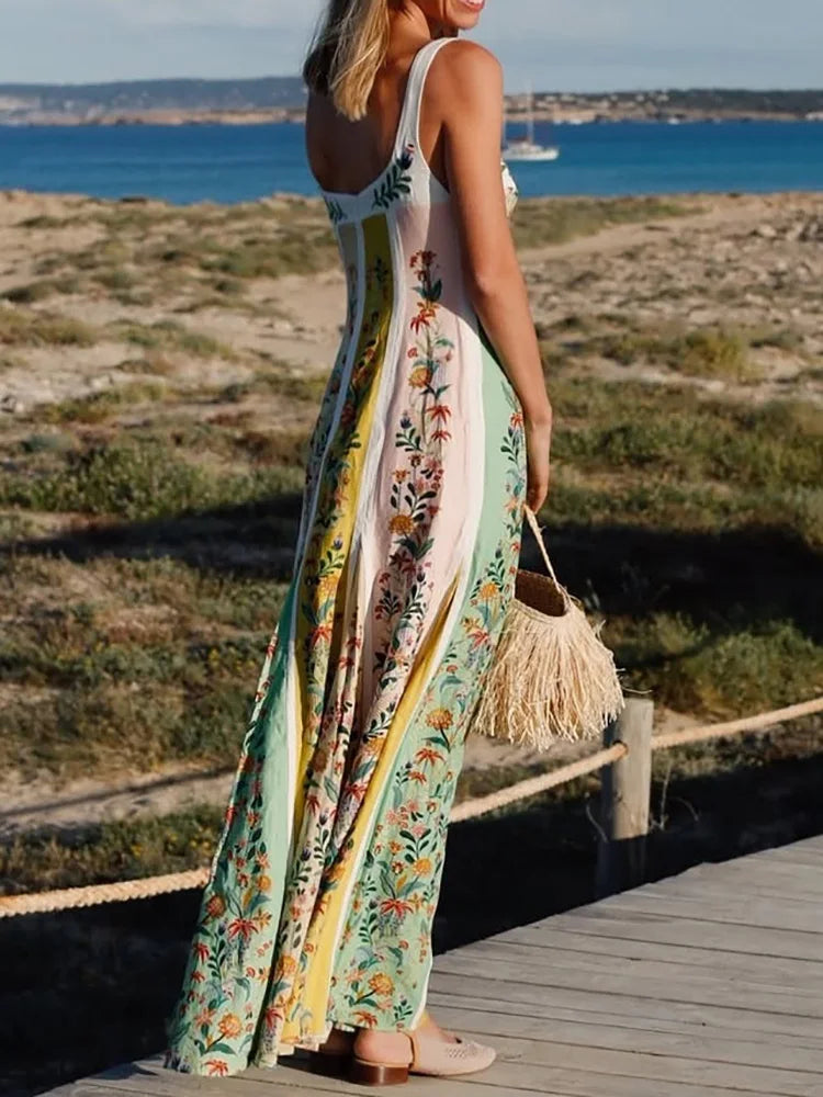 Woman in a floral dress standing on a wooden path by the sea