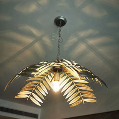 A dramatic iron palm leaf chandelier hanging in a modern dining room with natural light streaming in. B