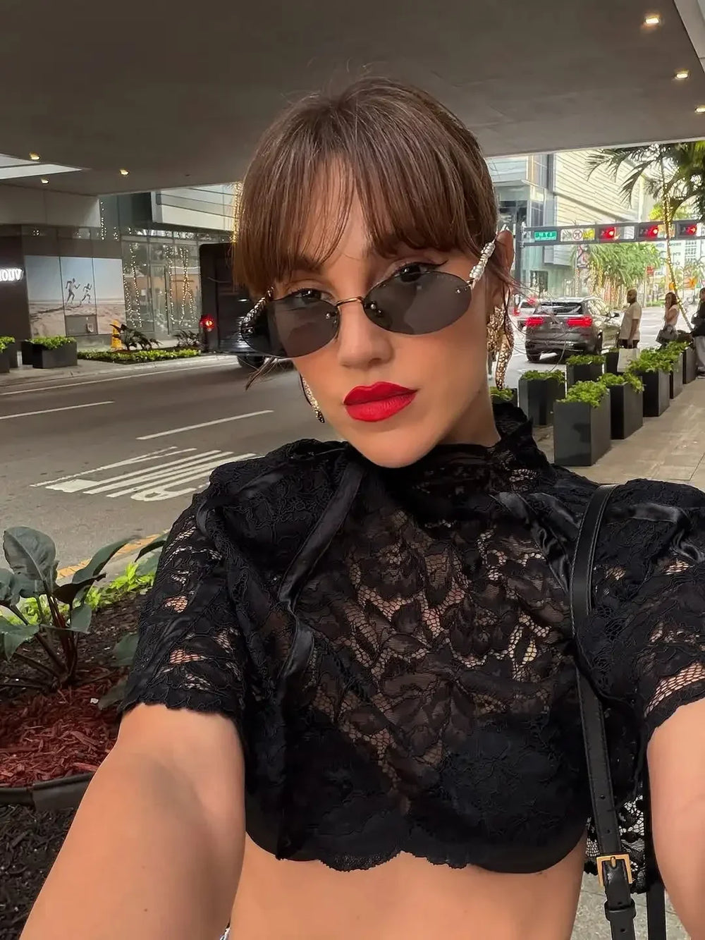 Woman wearing a black lace top and sunglasses outdoors.