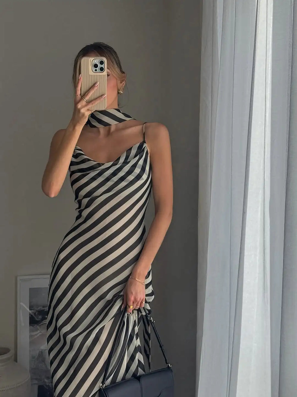 Person wearing a black and white striped dress taking a mirror selfie.