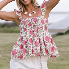 Woman wearing a floral top with pink and green pattern outdoors