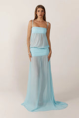 Woman wearing a light blue dress with a sheer overlay on a plain background