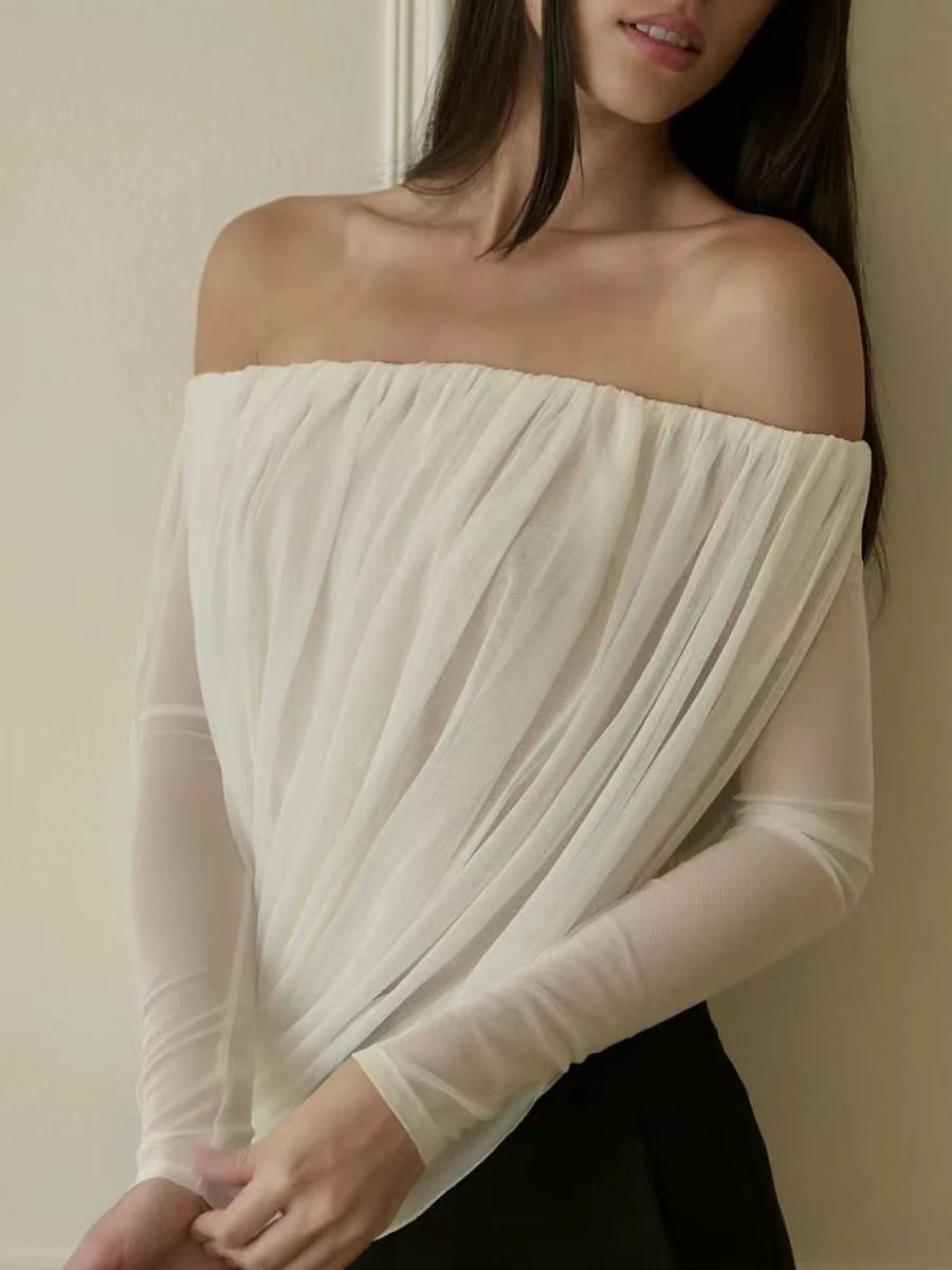 Woman wearing a white off-shoulder top against a neutral background