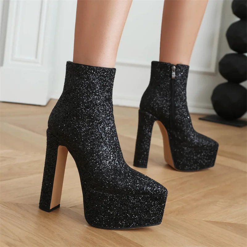 Black glittery platform high-heeled boots on a wooden floor.