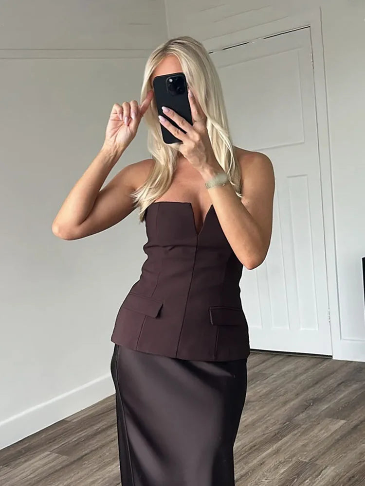 Woman taking a mirror selfie wearing a strapless brown top and skirt set.