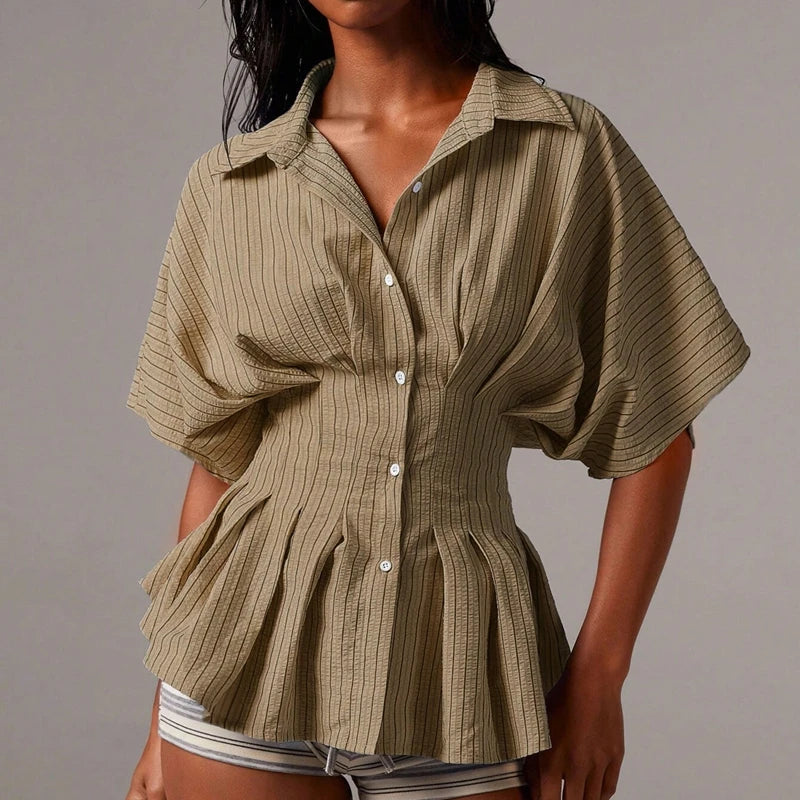 Woman wearing a khaki striped shirt with puffed sleeves on a grey background