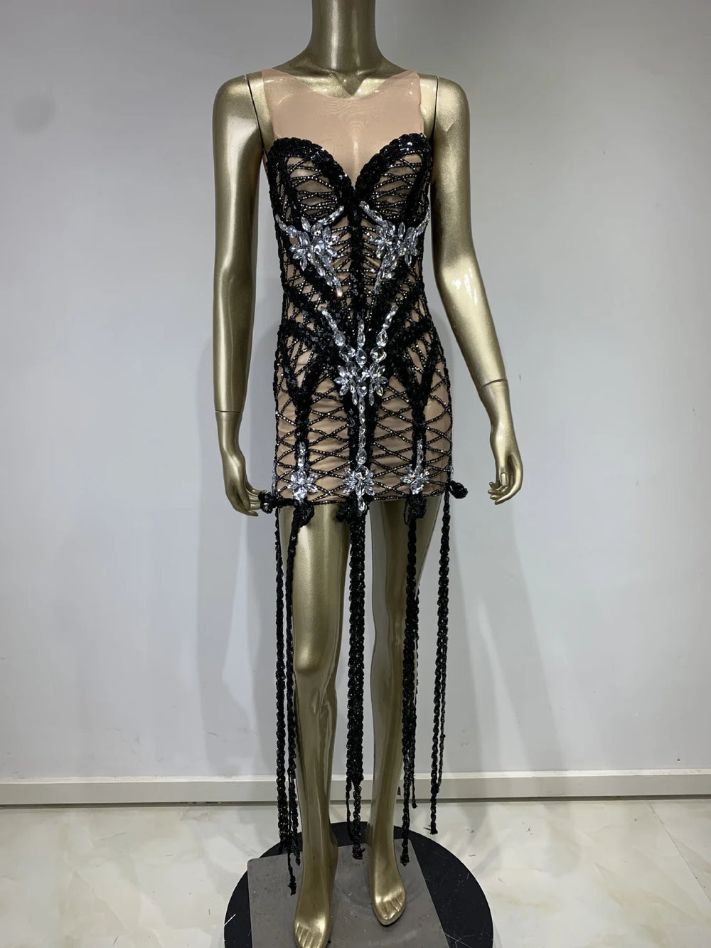 Black lace dress with sequins on a mannequin against a plain background