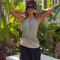Woman posing in a garden wearing a draped halter neck sleeveless knit top
