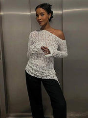 Woman wearing a white off-shoulder sweater and black pants in an elevator.