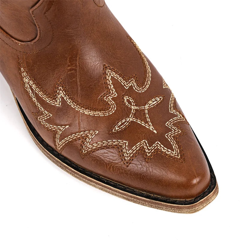 Close-up of pointed toe on brown faux leather western boots with embroidery