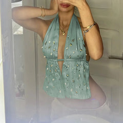 Person wearing a light green halter top with embellishments in a bathroom setting.