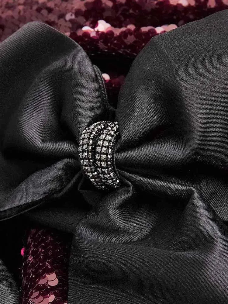 Black bow with a central decorative ring on a dark background