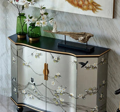 Decorative cabinet with floral patterns and green vases on a marble floor.