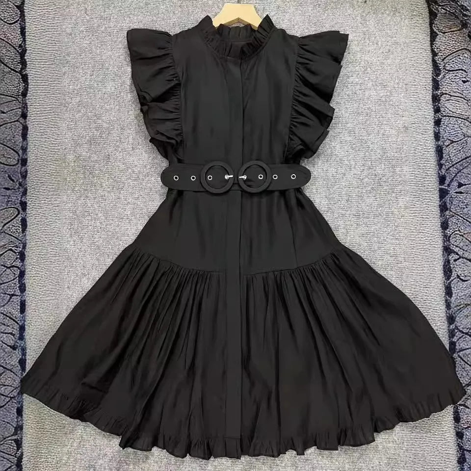 Black dress with ruffled sleeves and belt on a textured surface