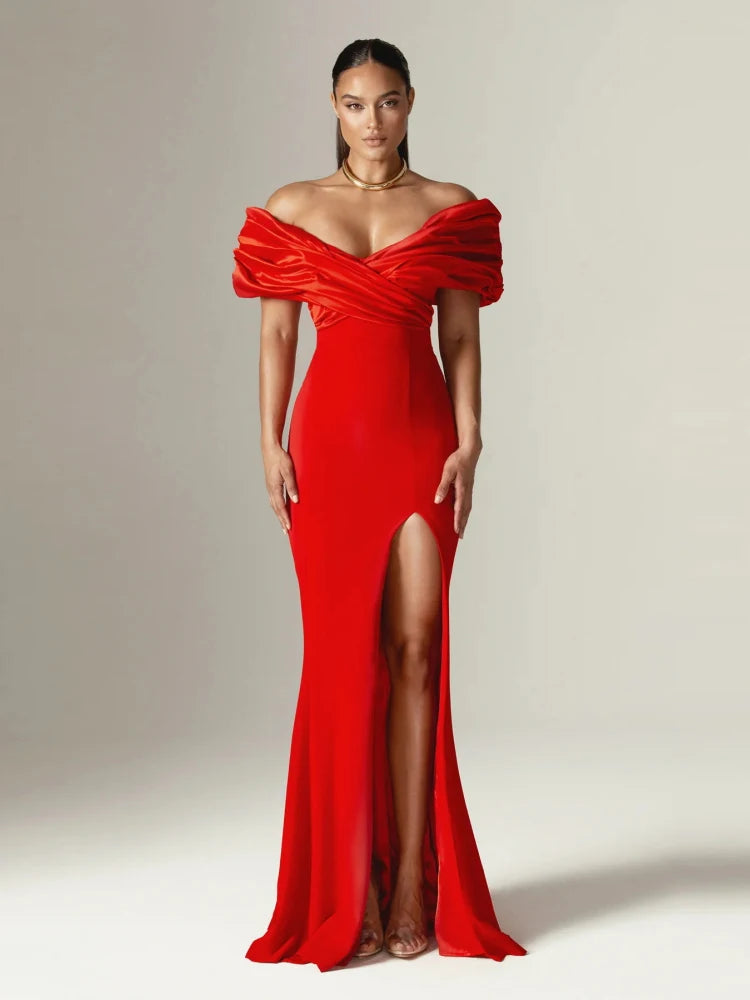 Woman wearing a red off-shoulder gown with a high slit on a plain background