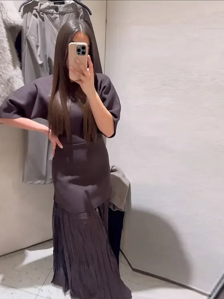 Person wearing a dark gray dress taking a mirror selfie.