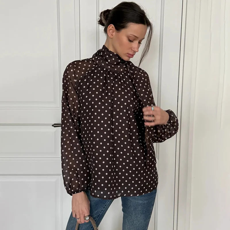 Woman wearing a brown polka dot blouse against a white background