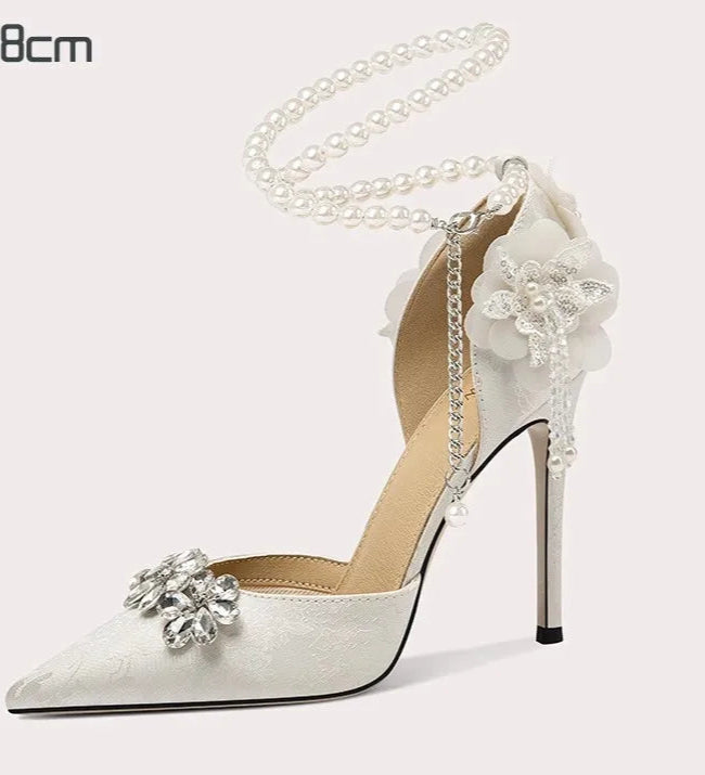 White high-heeled shoe with floral decorations on a light gray background