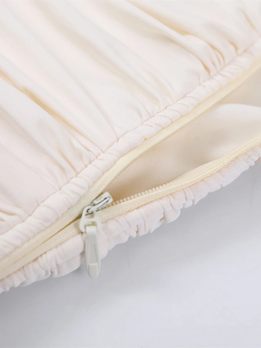 Close-up of a beige quilted cover with a zipper on a light gray background