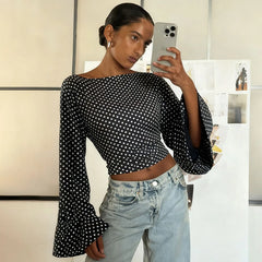 Woman taking a mirror selfie wearing a black polka dot top and light blue jeans.