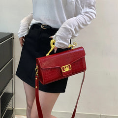 Red embossed top handle bag held by a woman