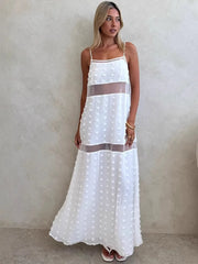 Woman wearing a white dress with sheer panels against a plain background