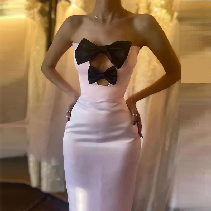 White strapless dress with black bow details on a blurred background