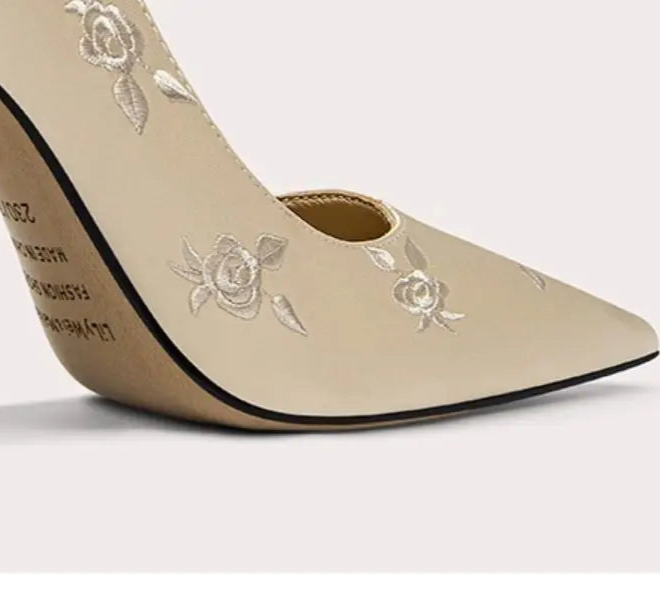 Beige high-heeled shoe with floral embroidery on a light background