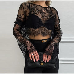 Person wearing a black lace top and gloves with a plain background
