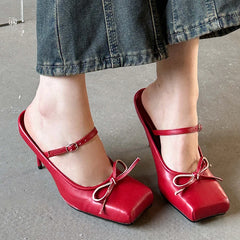 A pair of elegant butterfly-knot square toe pumps with a thin heel. Red