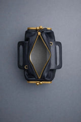 Black leather pouch with gold zipper and hardware on a gray background