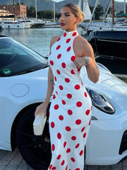 Polka dot halter neck maxi dress standing next to a white car.