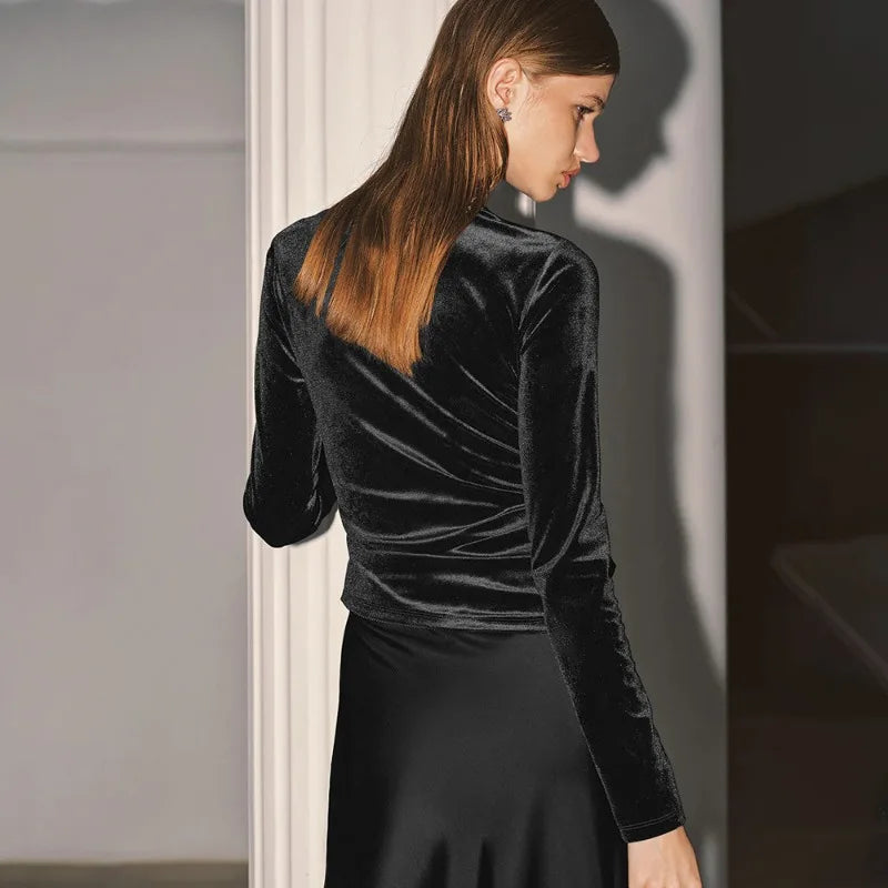 Woman wearing a black velvet top and skirt in a neutral setting