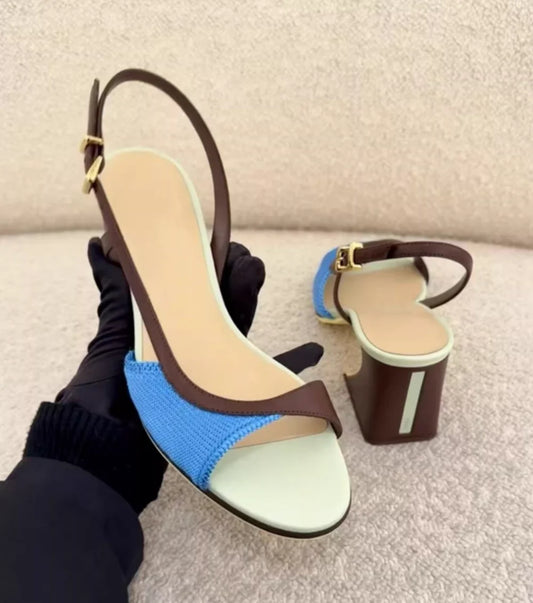 Close-up of a hand holding a colorblock slingback block heel.