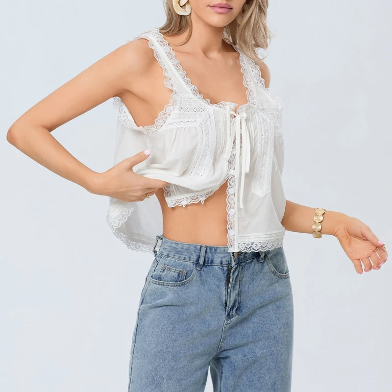 Woman wearing a white lace top and blue jeans on a light gray background