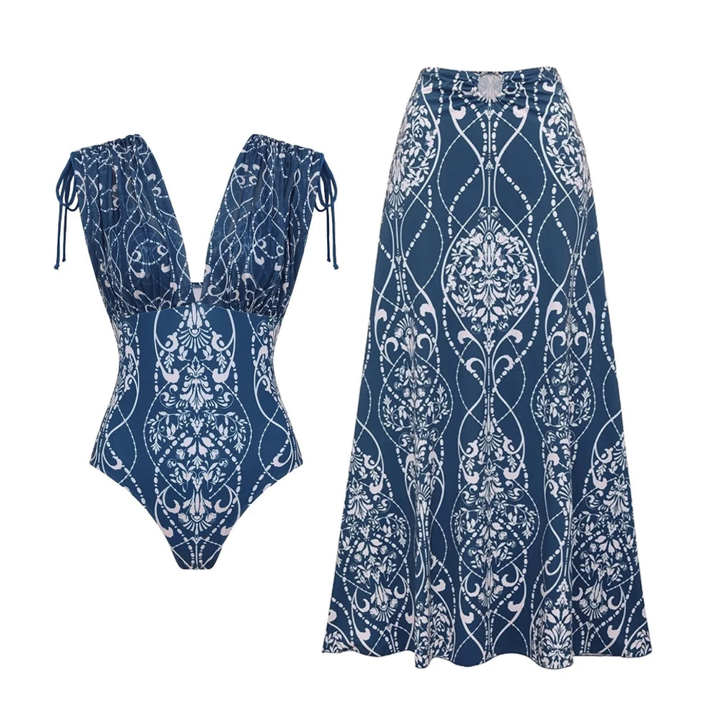 Blue and white architectural print two-piece swimwear set laid flat, including a plunge neckline top and maxi skirt.