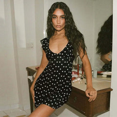 Woman wearing a black polka dot dress in a room.