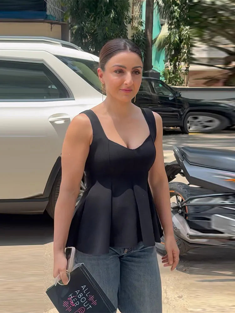 Woman in a black top and jeans standing outdoors with cars in the background