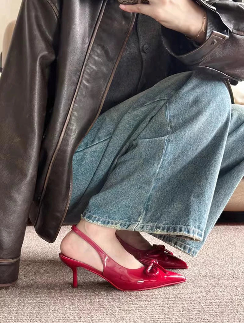 Person wearing red high heels, blue jeans, and a brown leather jacket.