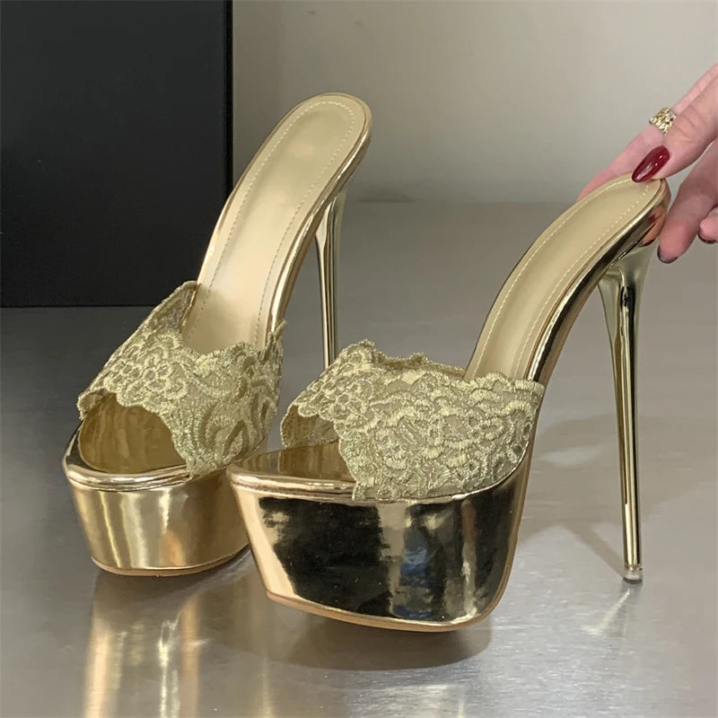 Gold high-heeled shoes with lace details on a reflective surface.