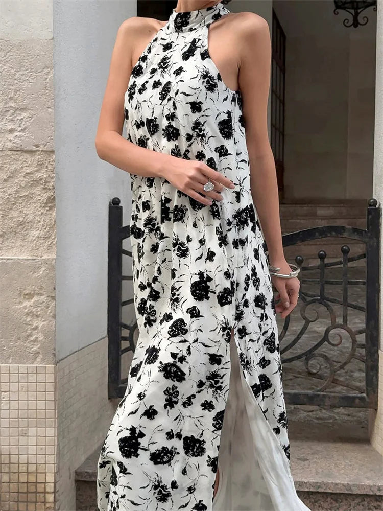 Woman wearing a white dress with black floral pattern standing outdoors.