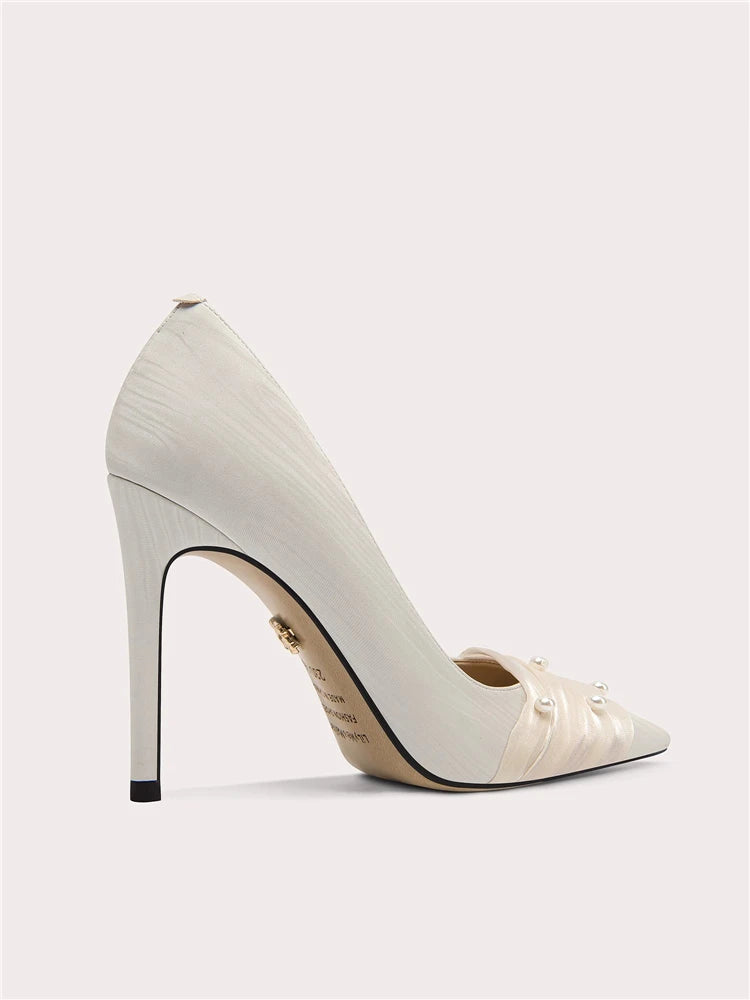 White high-heeled shoe with decorative elements on a light gray background