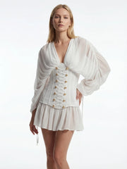 Woman wearing a white outfit with gold buttons on a white background
