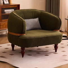Green armchair with a cushion on a patterned rug in a room.