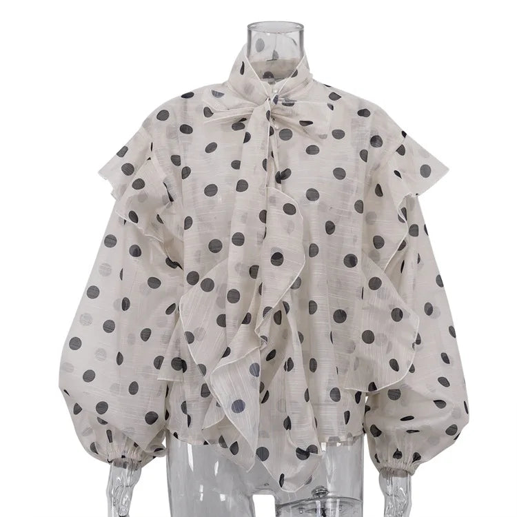 Polka dot blouse with ruffled collar on a mannequin against a white background